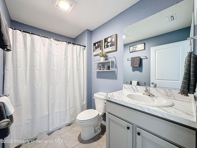 bathroom with toilet, vanity, tile patterned floors, and walk in shower