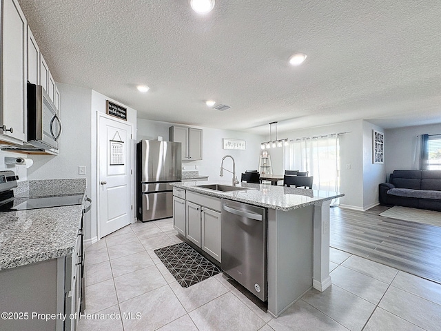 3337 Autumn Amber Dr, Spring Hill, FL 34609 - kitchen with stainless steel appliances, gray cabinetry, light tile patterned floors, open floor plan, and a textured ceiling