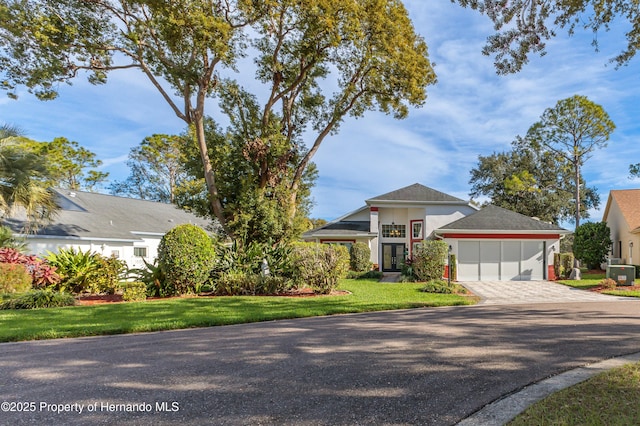 view of front of property featuring central AC unit, a garage, and a front lawn