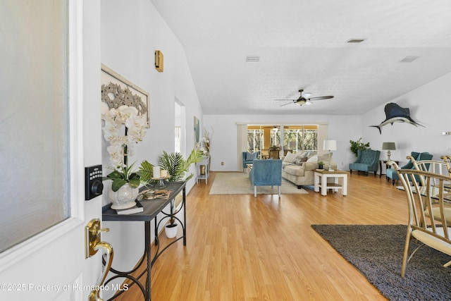 living room featuring hardwood / wood-style floors, ceiling fan, a textured ceiling, and vaulted ceiling