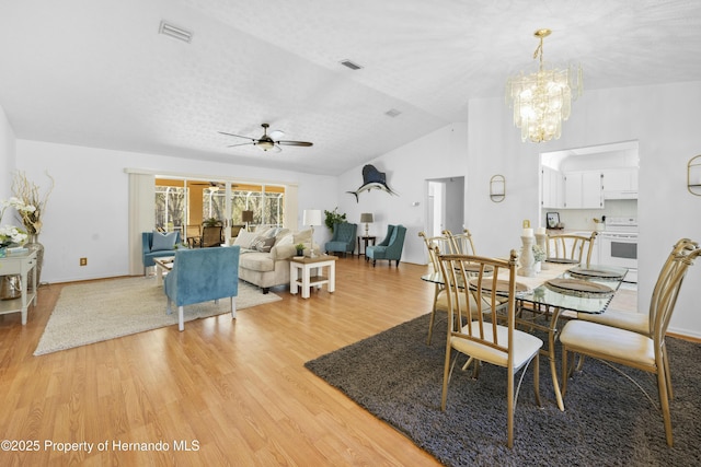 dining area featuring vaulted ceiling, light hardwood / wood-style flooring, a textured ceiling, and ceiling fan with notable chandelier