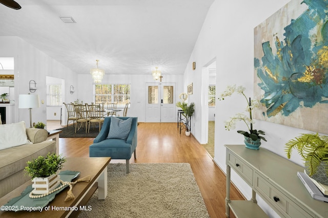 living room with a chandelier, light hardwood / wood-style flooring, and lofted ceiling