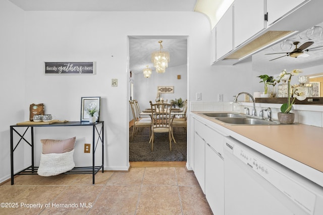 kitchen with ceiling fan with notable chandelier, white dishwasher, sink, decorative light fixtures, and white cabinetry