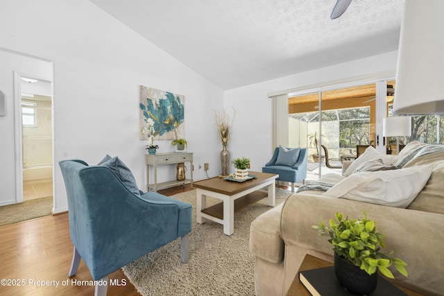 living room featuring wood-type flooring, a textured ceiling, vaulted ceiling, and ceiling fan