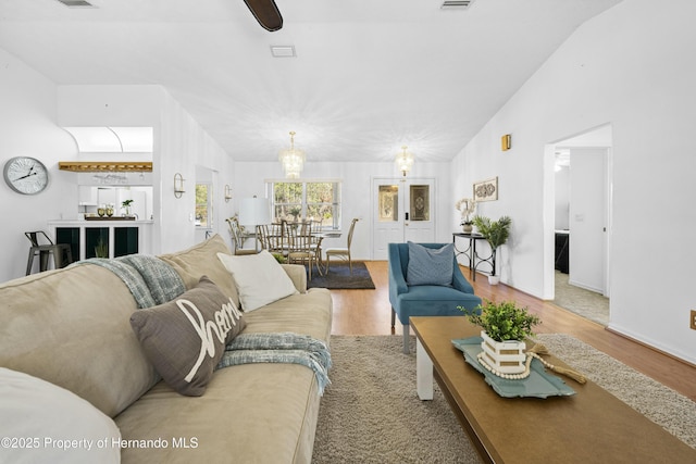 living room with hardwood / wood-style floors, an inviting chandelier, and lofted ceiling