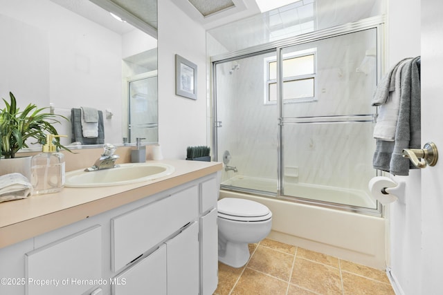 full bathroom featuring shower / bath combination with glass door, tile patterned flooring, vanity, and toilet