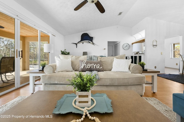 living room with ceiling fan, plenty of natural light, light hardwood / wood-style floors, and vaulted ceiling