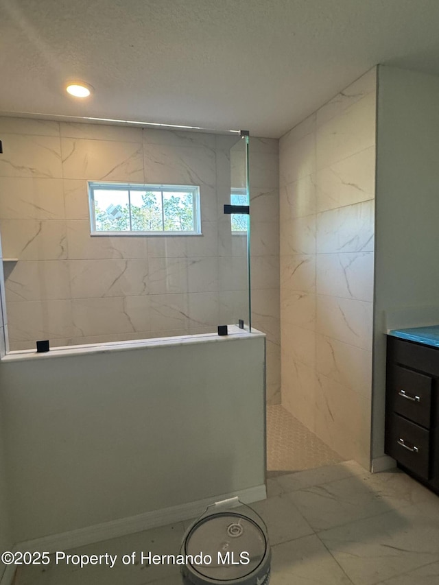 bathroom with vanity, tiled shower, and a textured ceiling