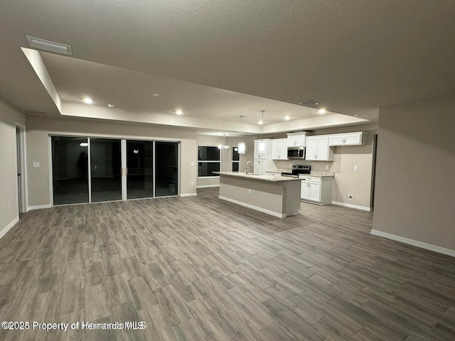 unfurnished living room featuring a textured ceiling, a tray ceiling, hardwood / wood-style flooring, and sink