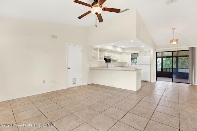 kitchen with kitchen peninsula, ceiling fan with notable chandelier, light tile patterned floors, white fridge, and white cabinetry