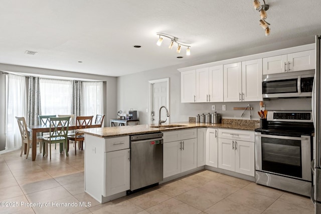 37351 Neighbors Path, Zephyrhills, FL 33542 - kitchen with kitchen peninsula, stainless steel appliances, white cabinets, dark stone counters, and sink