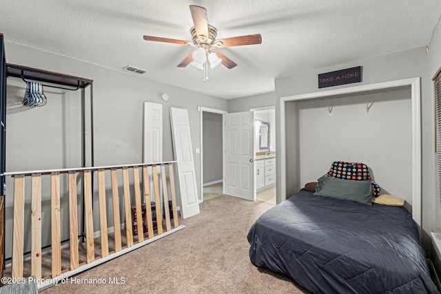 37351 Neighbors Path, Zephyrhills, FL 33542 - carpeted bedroom with connected bathroom, a closet, ceiling fan, and a textured ceiling