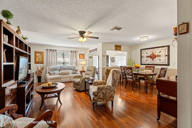 living room featuring hardwood / wood-style flooring, ceiling fan, and a textured ceiling