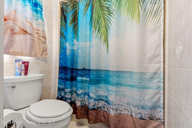 bathroom featuring tile walls and toilet