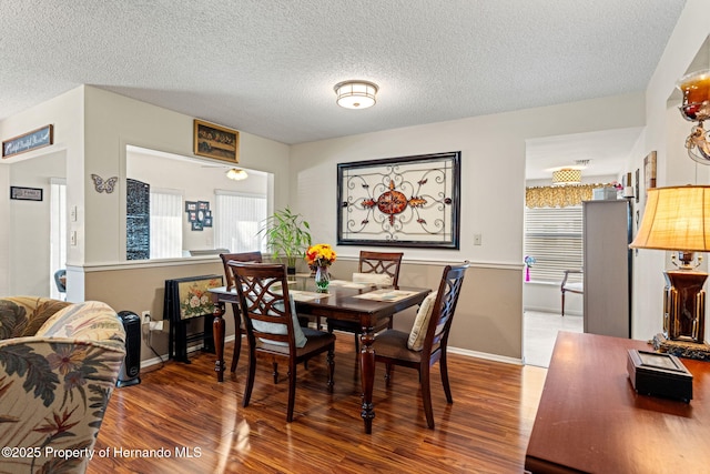 dining space with wood-type flooring and a textured ceiling