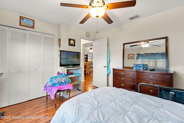 bedroom featuring ceiling fan, a closet, a textured ceiling, and light hardwood / wood-style flooring