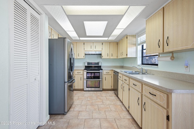 kitchen featuring a skylight, sink, stainless steel appliances, light brown cabinetry, and light tile patterned flooring