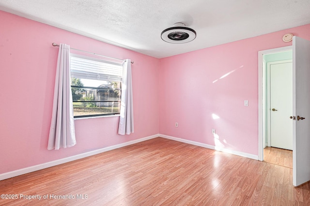 unfurnished room with a textured ceiling and light wood-type flooring