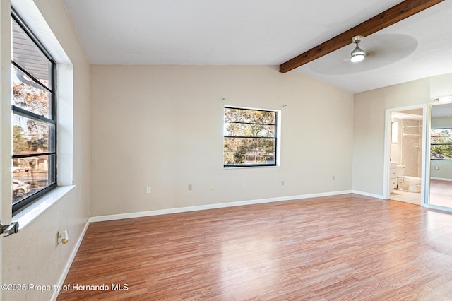 spare room featuring lofted ceiling with beams, light hardwood / wood-style floors, and a wealth of natural light