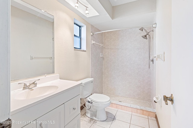 bathroom featuring tile patterned flooring, vanity, tiled shower, and toilet