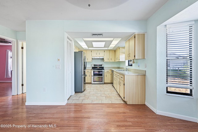 kitchen with sink, stainless steel appliances, light brown cabinetry, and light hardwood / wood-style flooring