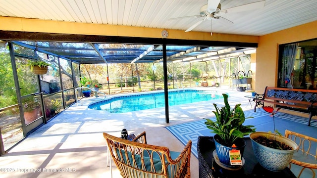 view of pool featuring a patio, glass enclosure, and ceiling fan