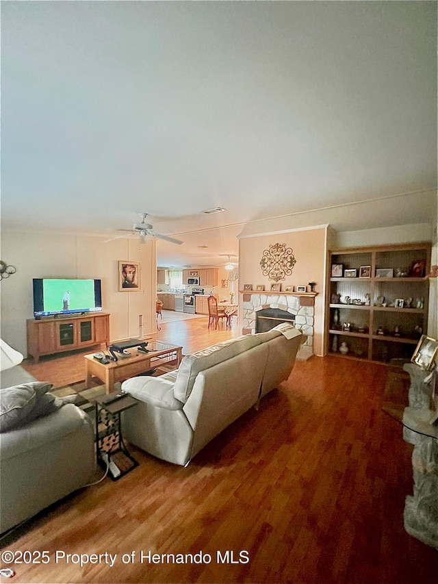 living room featuring a fireplace, wood-type flooring, and ceiling fan