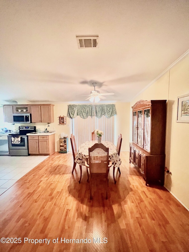 dining area featuring ceiling fan, light wood-type flooring, and crown molding