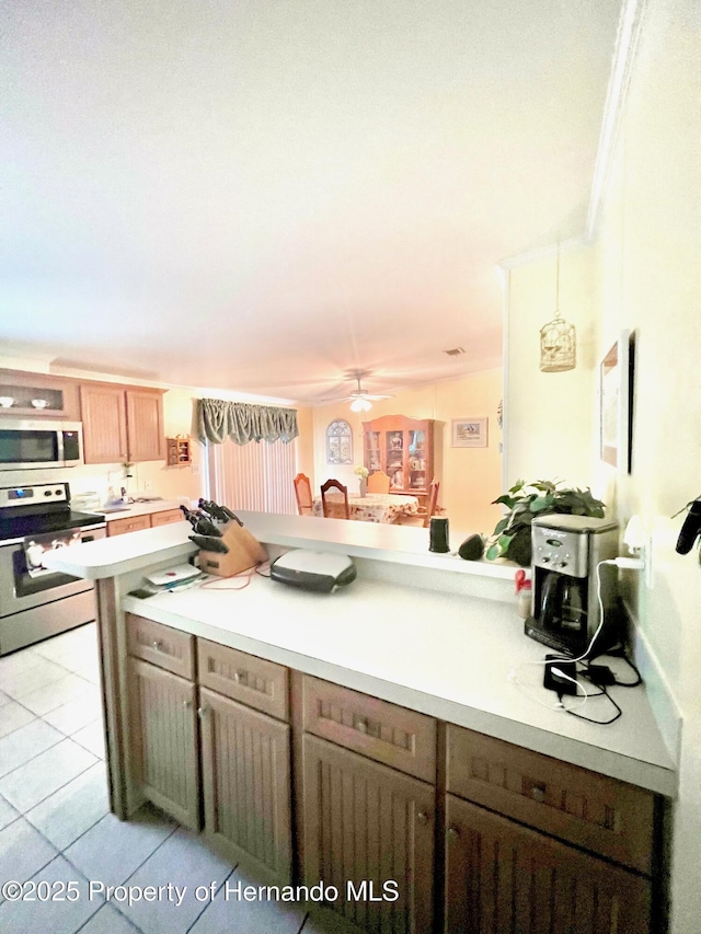 kitchen with kitchen peninsula, appliances with stainless steel finishes, ornamental molding, ceiling fan, and light tile patterned flooring