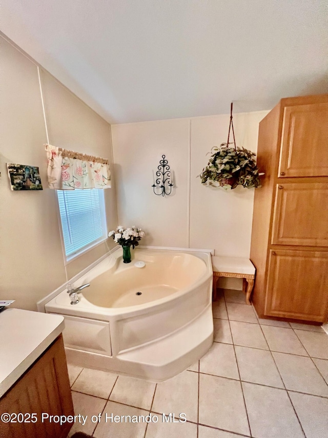 bathroom featuring a washtub, vanity, tile patterned flooring, and lofted ceiling