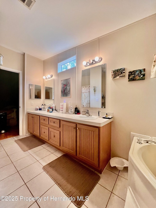 bathroom with tile patterned floors, a bathtub, and vanity