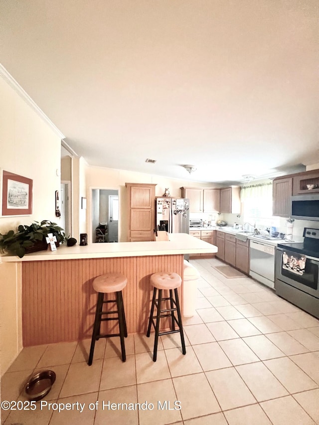 kitchen featuring a kitchen bar, appliances with stainless steel finishes, kitchen peninsula, and light tile patterned floors