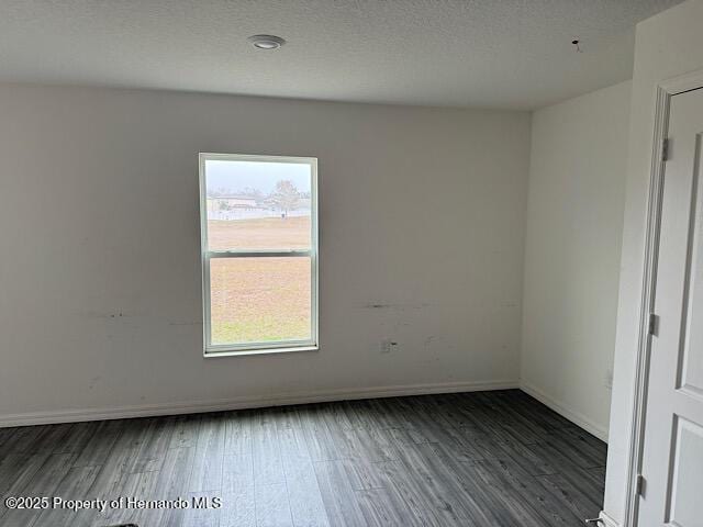 empty room featuring a healthy amount of sunlight and dark hardwood / wood-style flooring