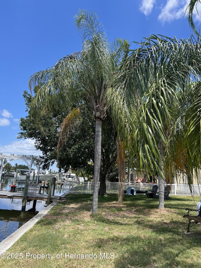 exterior space featuring a dock, a lawn, and a water view