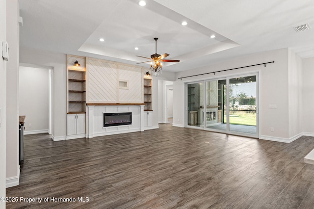 unfurnished living room with ceiling fan, a raised ceiling, and dark wood-type flooring