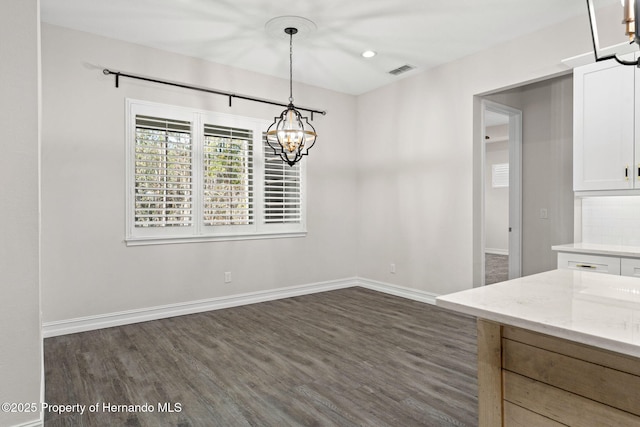 unfurnished dining area featuring dark hardwood / wood-style flooring and a chandelier