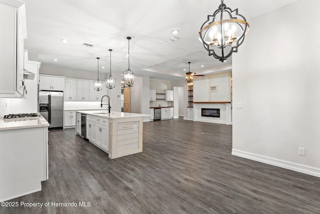 kitchen featuring a center island with sink, ceiling fan with notable chandelier, sink, hanging light fixtures, and stainless steel appliances