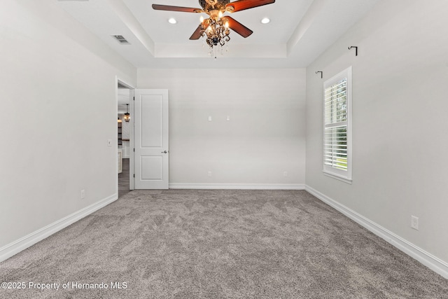 spare room featuring carpet floors, a tray ceiling, and ceiling fan