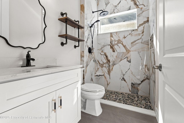 bathroom featuring toilet, tile patterned flooring, vanity, and tiled shower