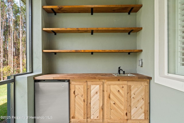 bar featuring refrigerator, butcher block countertops, and sink