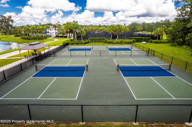 view of tennis court featuring a water view, a lawn, and basketball hoop