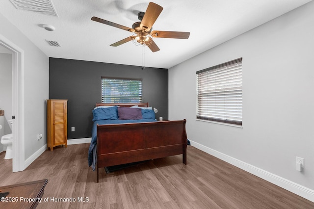 bedroom with wood-type flooring, ensuite bathroom, and ceiling fan