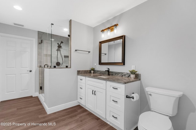 bathroom with hardwood / wood-style floors, vanity, an enclosed shower, and toilet