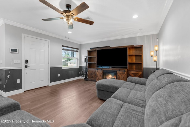 living room with wood-type flooring, ceiling fan, and crown molding