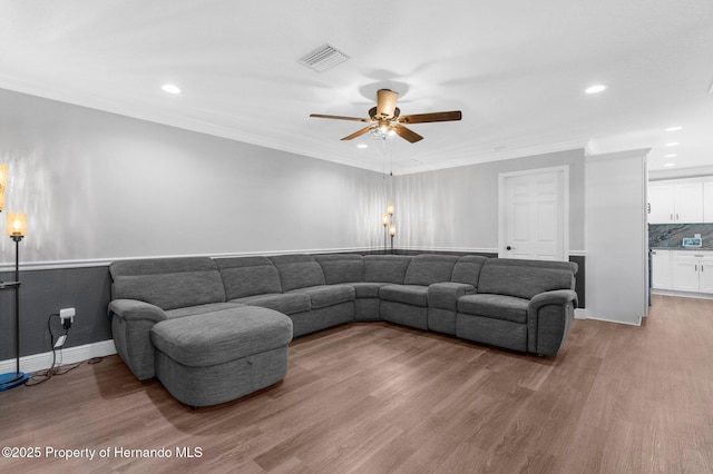 living room with hardwood / wood-style flooring, ceiling fan, and crown molding