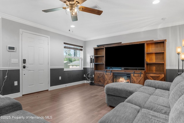 living room with wood-type flooring, ceiling fan, and ornamental molding