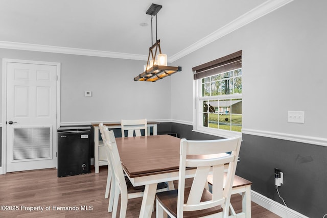 dining area with wood-type flooring and ornamental molding