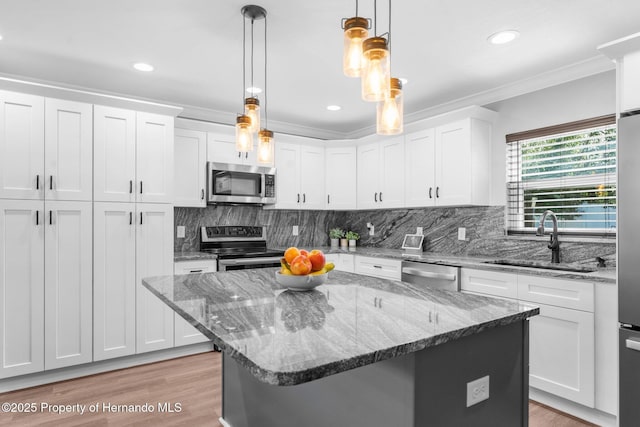 kitchen with decorative light fixtures, a center island, white cabinetry, and stainless steel appliances