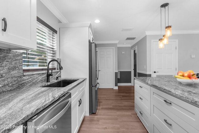 kitchen with white cabinets, sink, appliances with stainless steel finishes, decorative light fixtures, and light stone counters