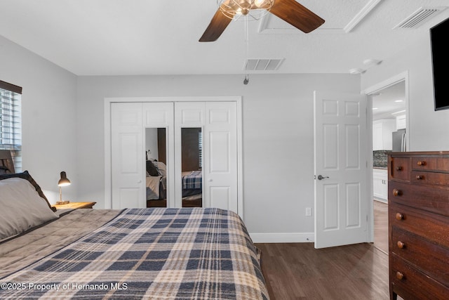 bedroom featuring ceiling fan, stainless steel fridge, dark hardwood / wood-style flooring, and a closet